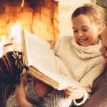Family smiling and reading a book by a fireplace